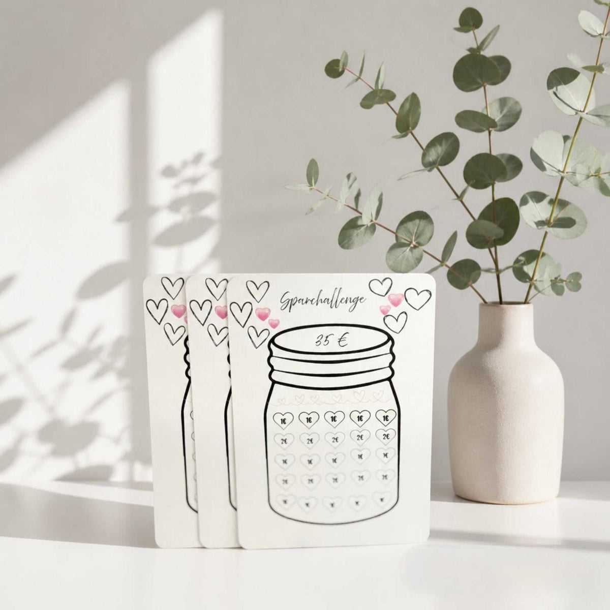 Sparglas Challenge 35€ als weiße Karte aus mattem Papier mit schwarzer Glaszeichnung, Herzen und 35-€-Beschriftung.
