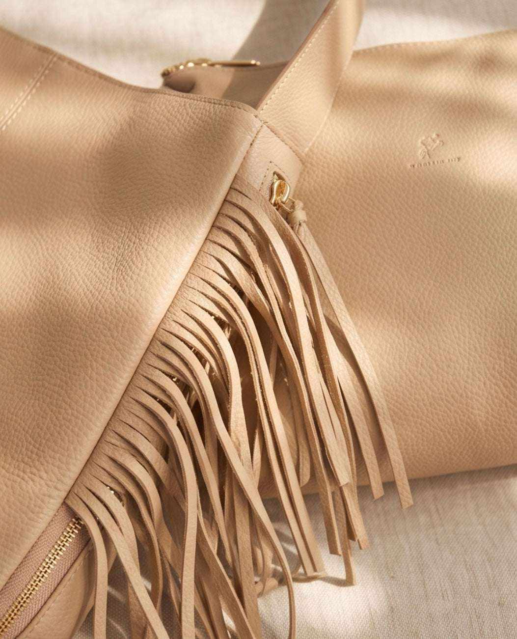 Damenhandtasche mit Fransen aus beigefarbenem, genarbtem Material mit langen seitlichen Fransen und goldfarbenem Reißverschluss