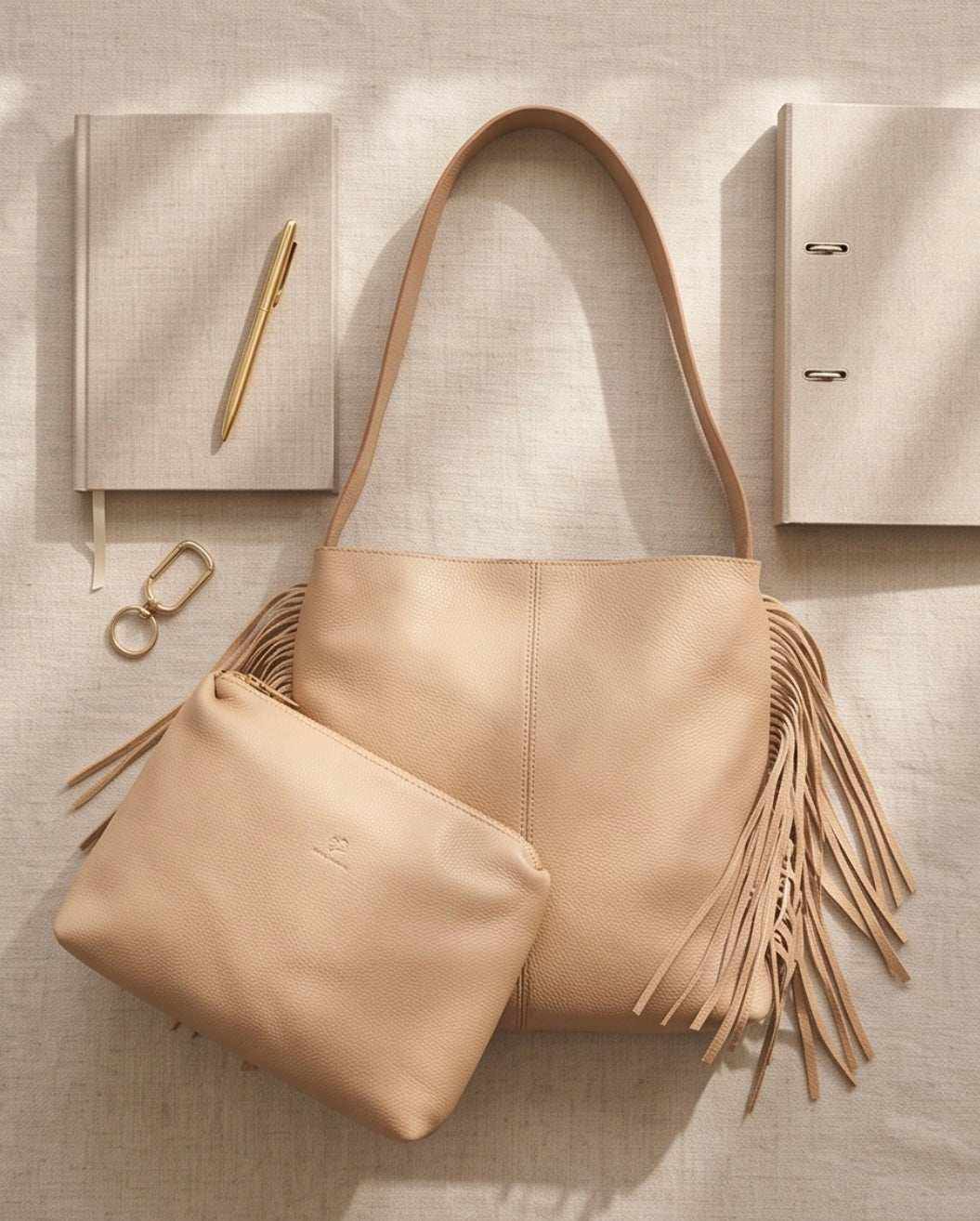 Damenhandtasche mit Fransen aus glattem beigefarbenem Material, mit langen Henkeln und passendem Täschchen